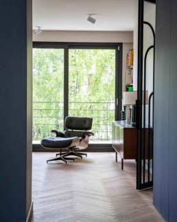 Fauteuil lounge cuir noir parquet chevron devant baie vitrée - Marque de Fabrik